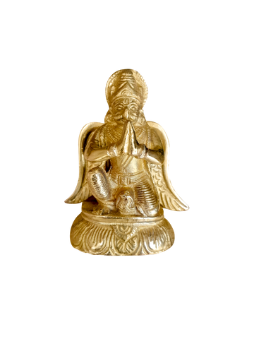 Golden Garud Dev statue in a prayerful pose on an ornate pedestal
