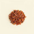 Natural orange and red Carnelian tumbled crystal chips arranged on an ivory background