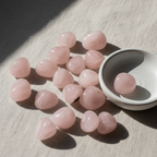 Polished Rose Quartz tumble stones arranged on a neutral linen surface
