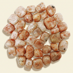 Polished Sunstone tumble stones arranged on a warm ivory background
