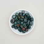 Bloodstone tumble stones arranged in a white ceramic dish