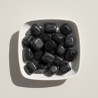 Black Tourmaline tumble stones arranged in a white ceramic dish