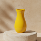 Bright yellow vase displayed on a light stone pedestal