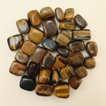 Polished Tiger's Eye tumble stones arranged on an ivory studio background