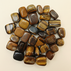 Polished Tiger's Eye tumble stones arranged on an ivory studio background