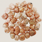 Close-up of polished Sunstone tumble stones on a light neutral beige background