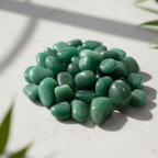 Polished green aventurine tumble stones arranged on a pale natural stone surface