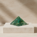 Green aventurine pyramid displayed on a light stone pedestal