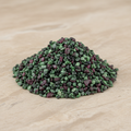 Ruby-Zoisite Crystal Chips arranged on a warm neutral stone surface