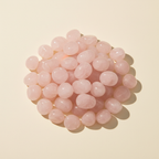 Polished Rose Quartz tumble stones arranged on an ivory studio background