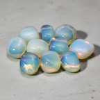 Polished Opalite tumble stones arranged on a pale natural stone surface