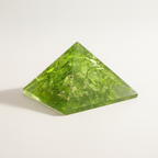 Elevated view of a bright green Peridot crystal pyramid with translucent facets