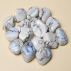 Polished Rainbow Moonstone tumble stones arranged on a warm ivory background