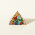 Front view of a multicolour 7 Chakra crystal pyramid on a warm white background