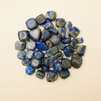 Polished Lapis Lazuli tumble stones arranged on an ivory studio background