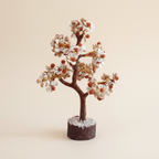 Rudraksha Gomti Chakra tree with pale stones, red accents, reddish-brown branches, and dark wood base on an ivory background