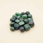 Polished Ruby Zoisite tumble stones arranged on an ivory studio background