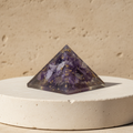 Purple amethyst pyramid displayed on a light stone pedestal