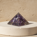 Purple amethyst pyramid displayed on a light stone pedestal