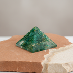Green aventurine pyramid on a warm terracotta and cream stone surface