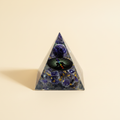 Amethyst crystal pyramid with a dark circular center motif on a warm ivory background