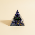 Amethyst crystal pyramid with a dark circular center motif on a warm ivory background