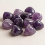 Close-up arrangement of Amethyst tumble stones on a light background