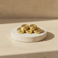 Compact cluster of round gold-toned pieces displayed on a light stone pedestal