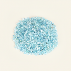 Loose Aquamarine tumbled stones and pale blue crystal chips arranged on an ivory studio background