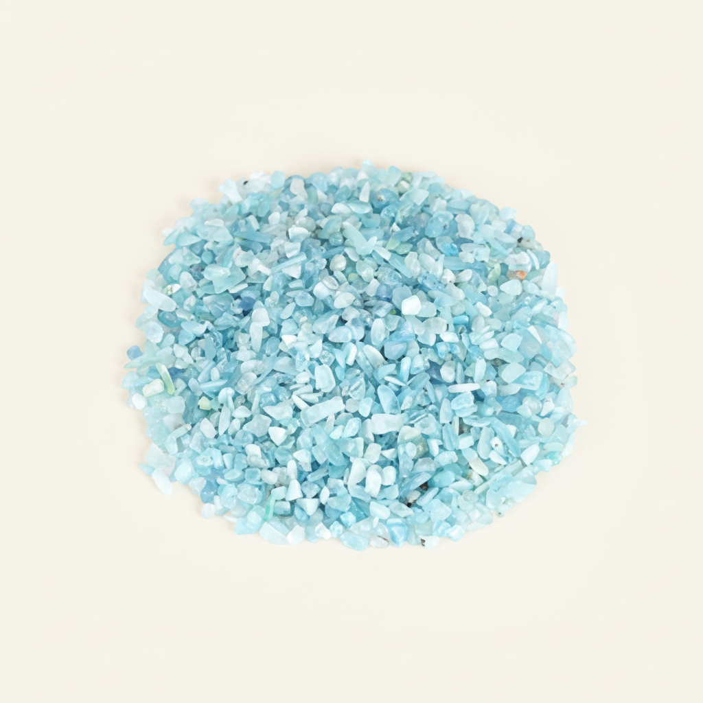 Loose Aquamarine tumbled stones and pale blue crystal chips arranged on an ivory studio background