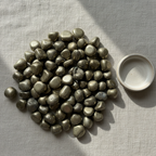 Polished Pyrite tumble stones arranged on a neutral linen surface