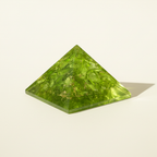 Side profile of a bright green Peridot crystal pyramid with faceted detail