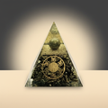 Triangular Pyrite pyramid with an embedded green-gold sphere and central coin-shaped design on a warm studio background