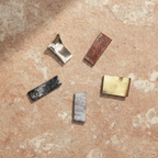 Five Panch Dhatu metal pieces on a warm terracotta and cream stone surface