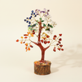 Seven Chakra crystal tree with rainbow-colour stones and a natural wood base on an ivory background