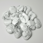 Close-up of polished Rainbow Moonstone tumble stones on a light neutral background