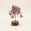 Amethyst crystal tree with purple chips, golden branches, and wood base on an ivory background