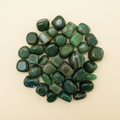 Polished Green Jade tumble stones arranged on an ivory studio background