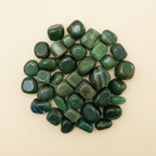 Polished Green Jade tumble stones arranged on an ivory studio background