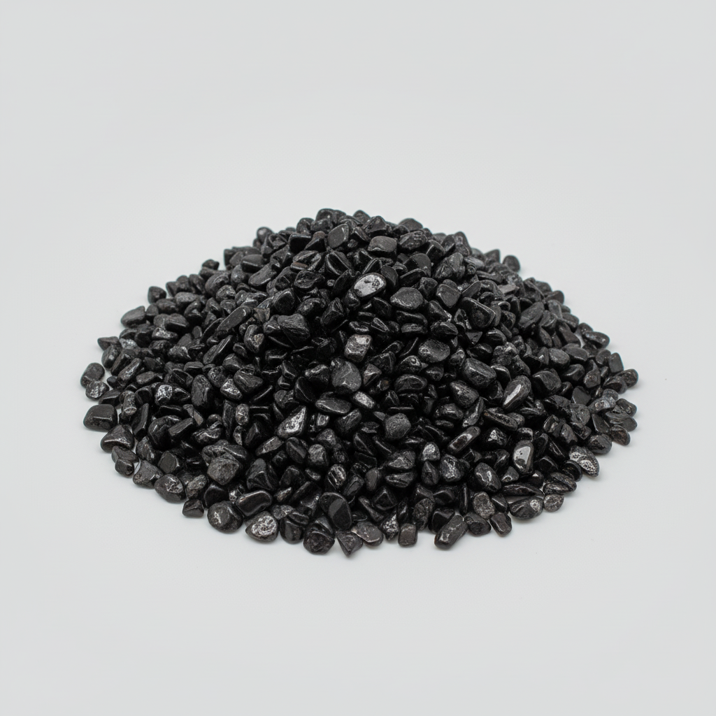 Loose Black Tourmaline tumbled stones and dark crystal chips arranged on a light studio background