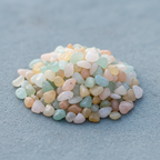Close-up of soft pastel Beryl crystal chips on a blue-grey surface